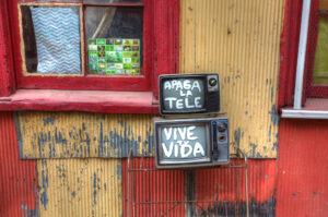 Two old televisions painted with the phrase "Apaga La Tele Vive Tu Vida" (Turn off the TV, Live your life)