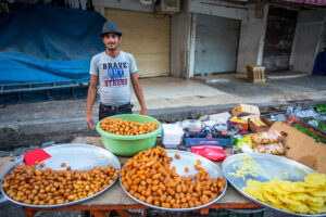 A food vendor at the market in Erbil Iraq wearing a shirt that reads "Brave but not Strong"